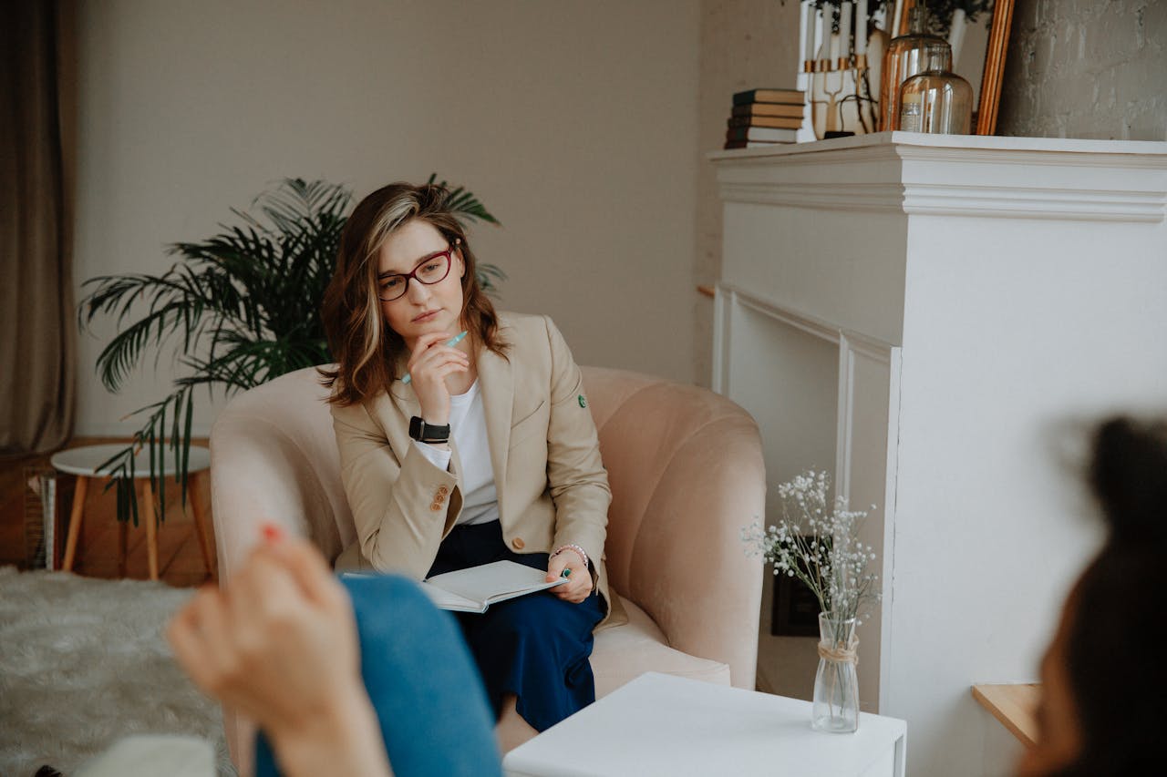 A thoughtful female therapist engages in a counseling session indoors, promoting mental well-being.